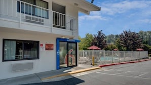 A building with a blue entrance, a sign reading 'Welcome', and a fenced pool area. - Spacious 2-bed Room|Pool|Free Wifi (Bellingham)