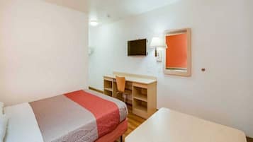 A hotel room with a bed, a desk, a chair, a TV, and a window.