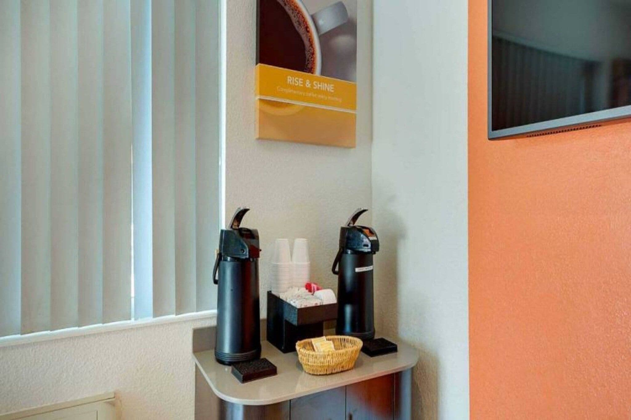 A coffee station with two coffee makers and a basket of cups.