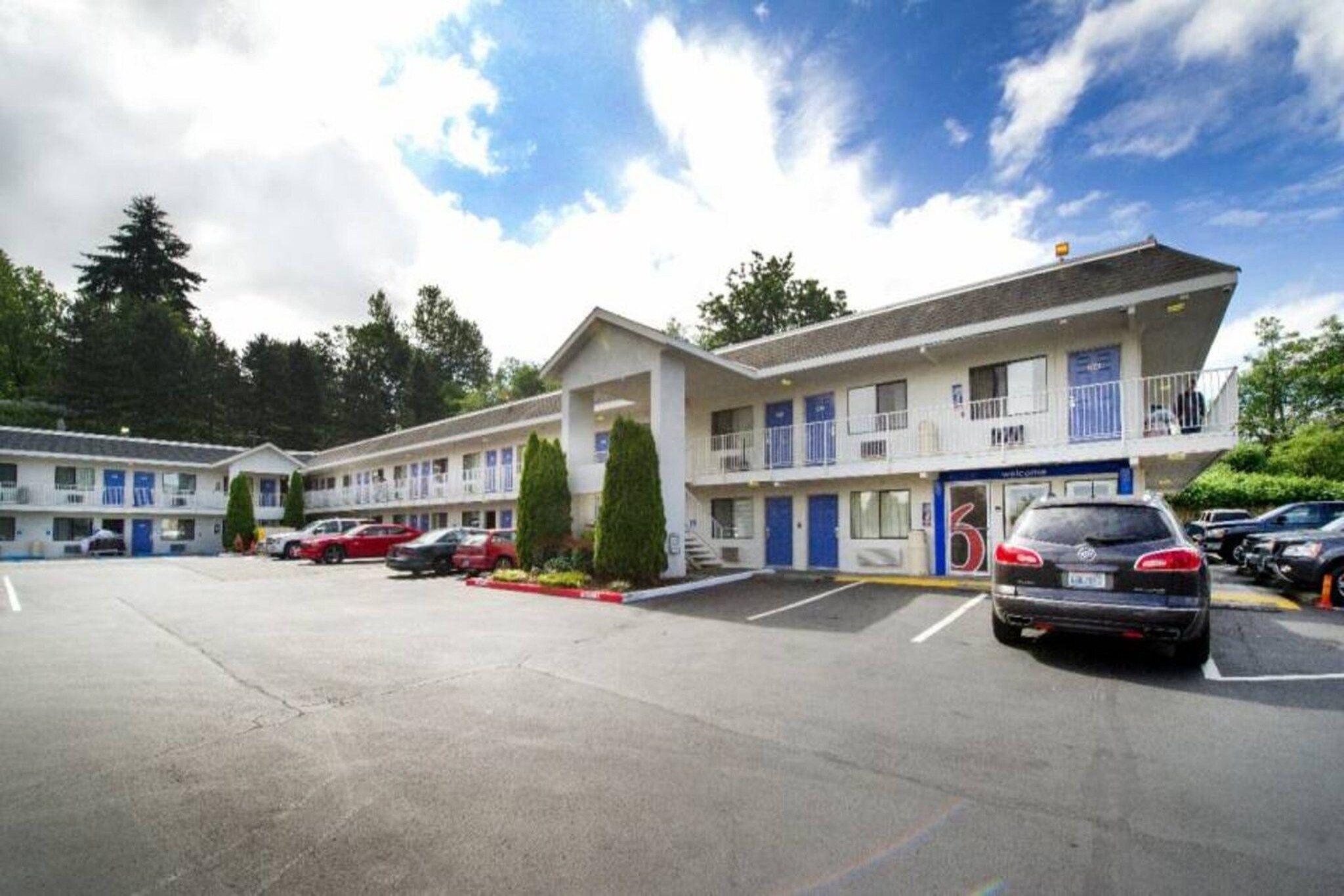 A motel with multiple-story buildings, a parking lot, and a clear sky.