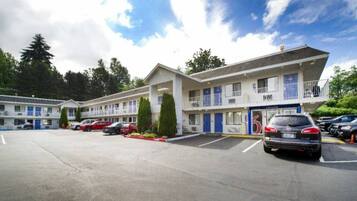 A motel with multiple-story buildings, a parking lot, and a clear sky.