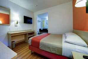 A hotel room with a bed, a desk, a chair, a television, and a bathroom visible through an open door. - 1 Queen Bed | Micfridge (Seattle)
