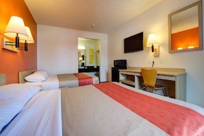 Quarto de hotel com duas camas, uma escrivaninha, uma cadeira e uma televisão.