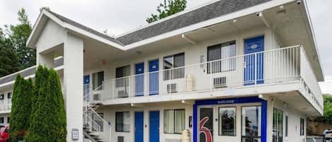 A two-story motel with a blue and white exterior, a visible entrance, and a parking lot in front.