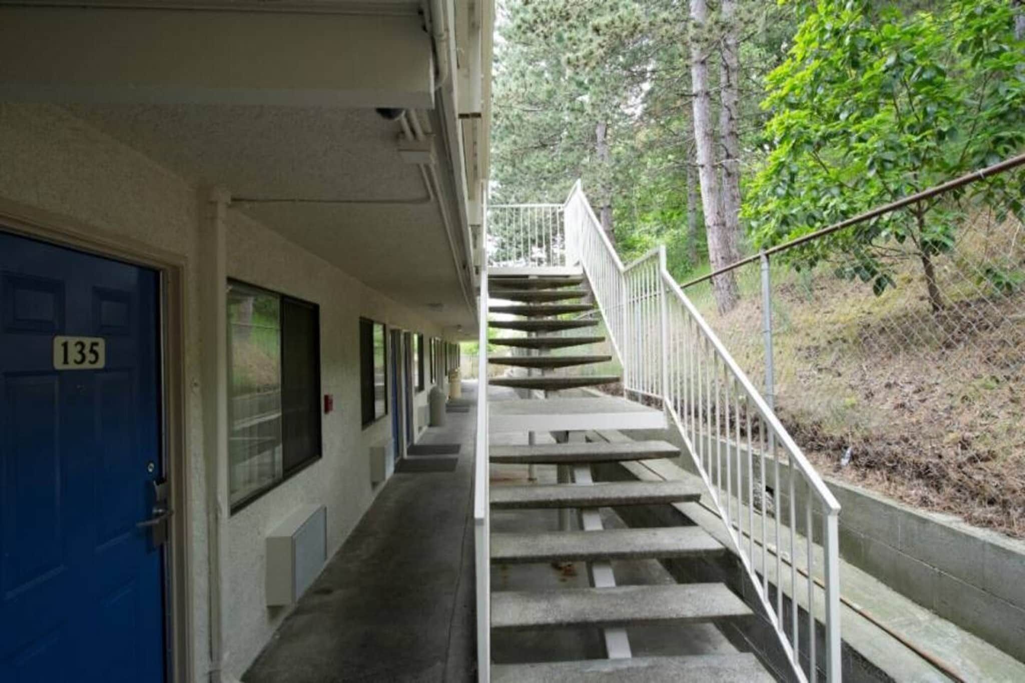 A building with a blue door marked with the number 135, a covered walkway, and a staircase leading to a higher level.