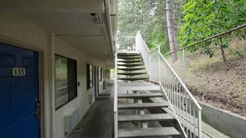 A building with a blue door marked with the number 135, a covered walkway, and a staircase leading to a higher level.