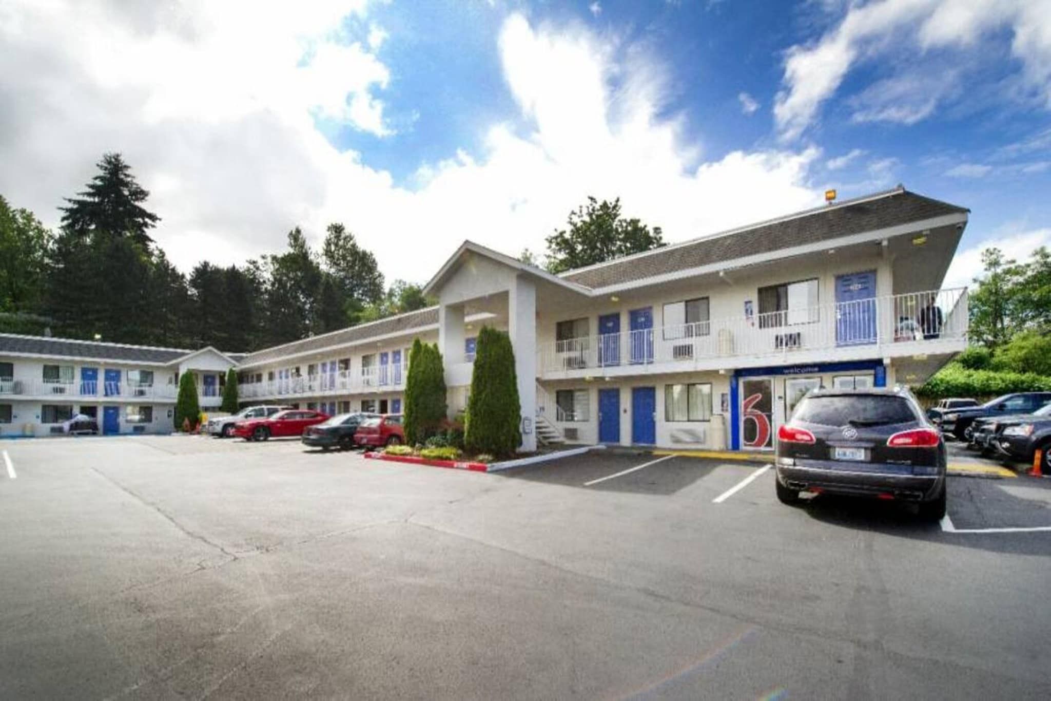 A motel with multiple rooms, a parking lot, and a clear sky.