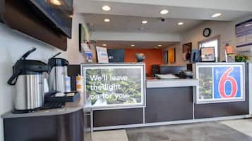 A hotel reception area with a coffee machine, a sign stating 'We'll leave the light on for you,' and a number '6' indicating the room number.