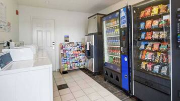 A vending machine area with snacks and beverages, a refrigerator, and a magazine rack.