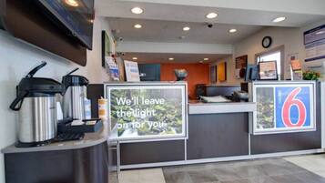 A hotel reception area with a coffee machine, a sign stating 'We'll leave the light on for you,' and a number '6' indicating the room number.