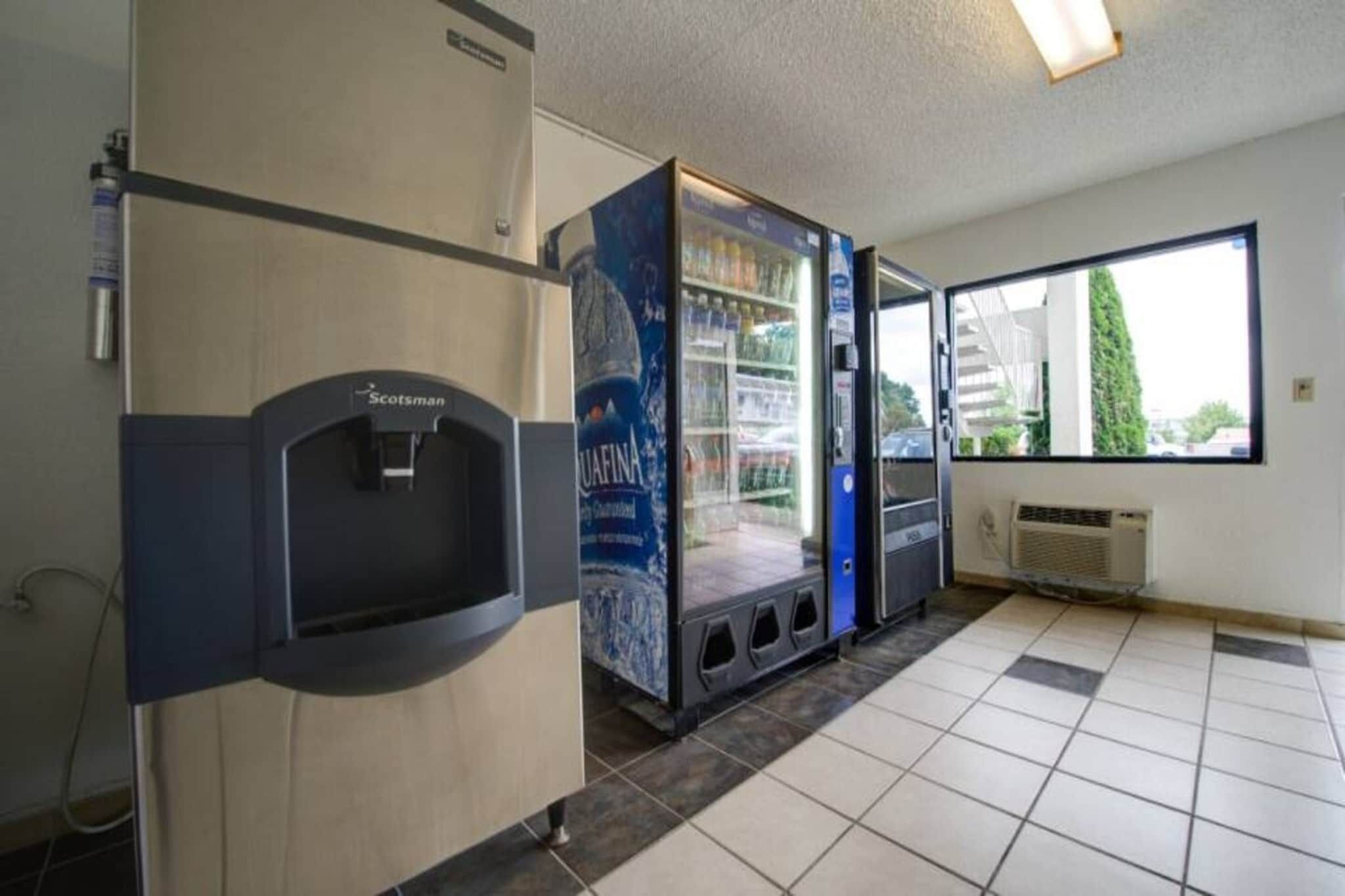 A restroom with a water dispenser, a hand dryer, and a poster advertising a product.