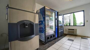 A restroom with a water dispenser, a hand dryer, and a poster advertising a product.