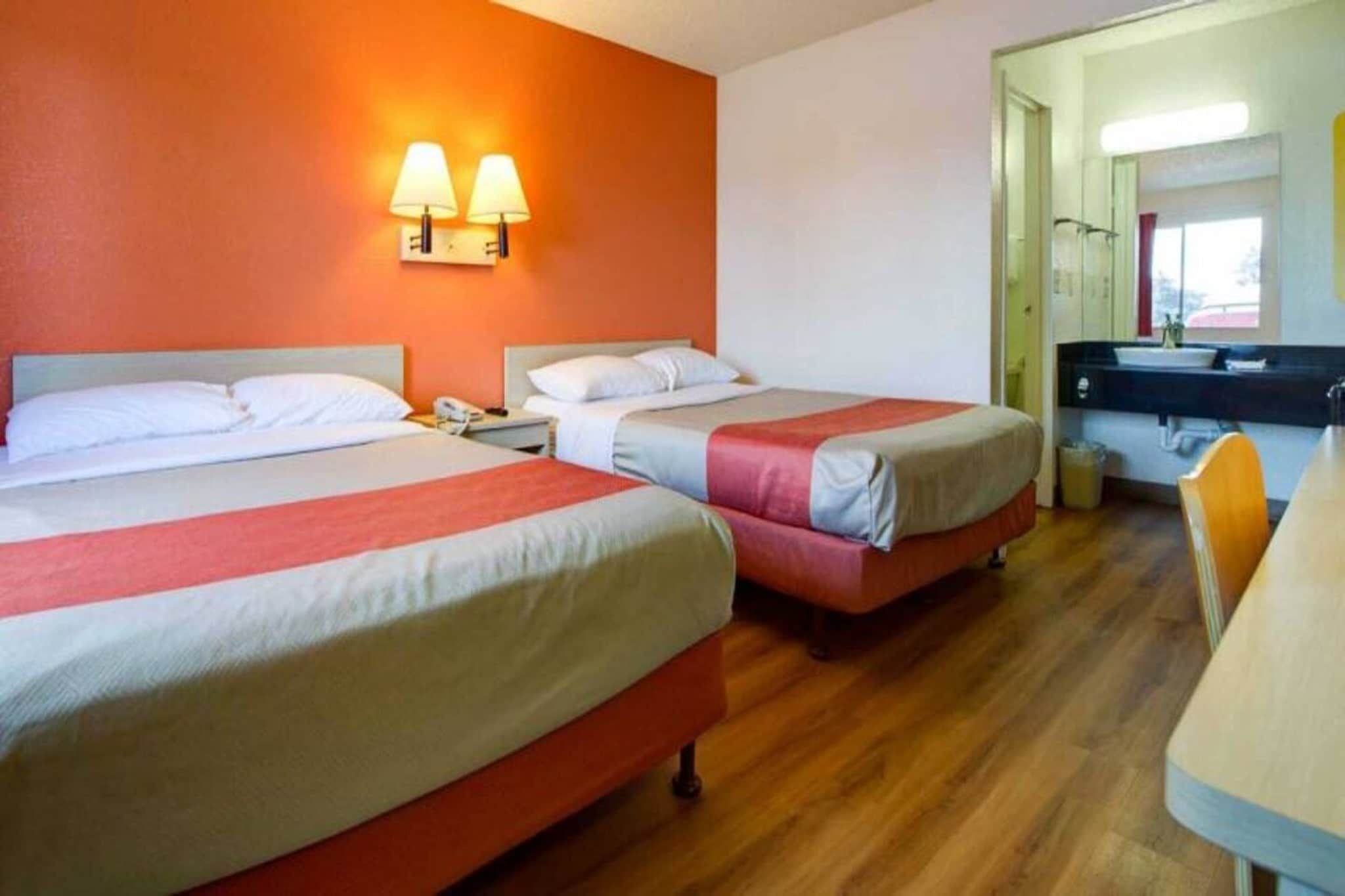 A hotel room with two beds, a bathroom, and a dining area.