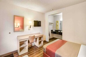 A hotel room with a bed, a desk, a chair, a mirror, and a bathroom visible through an open door. - 1 Full Bed | Non-Smoking (Everett)