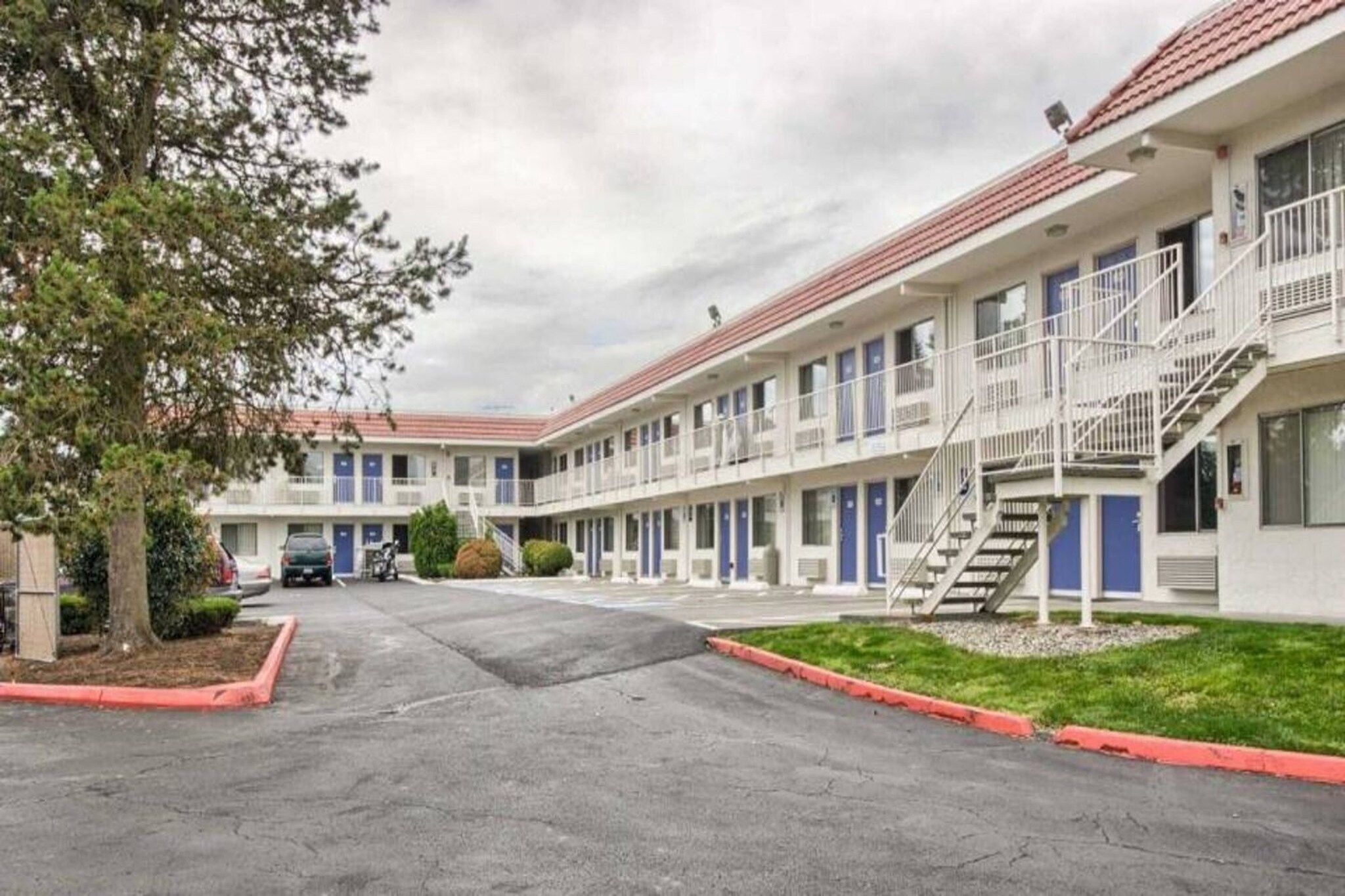 A motel with a central courtyard, multiple rooms with balconies, and a parking area.