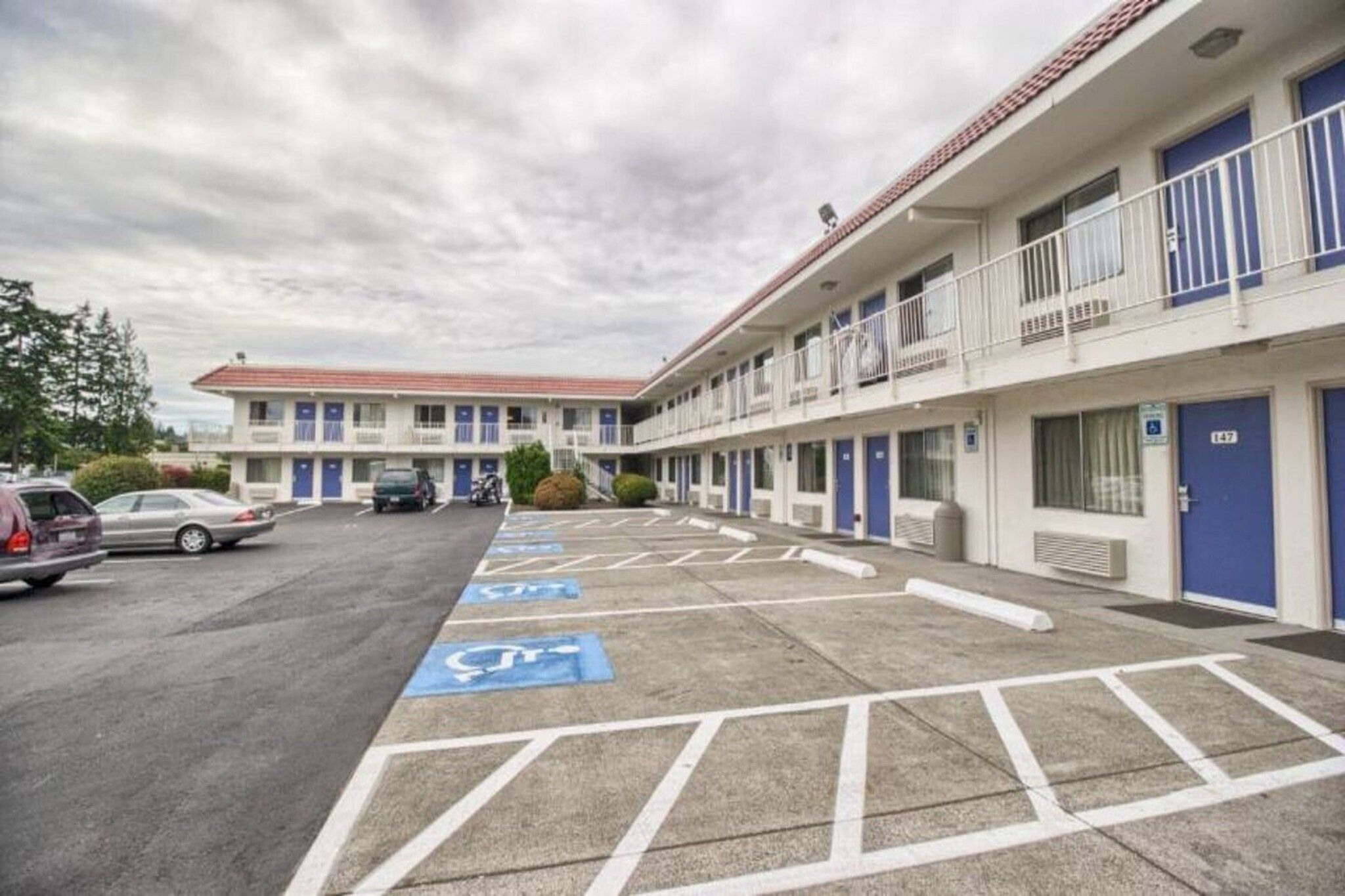 A motel with a parking lot marked for handicapped parking, a building with multiple balconies, and a clear sky.