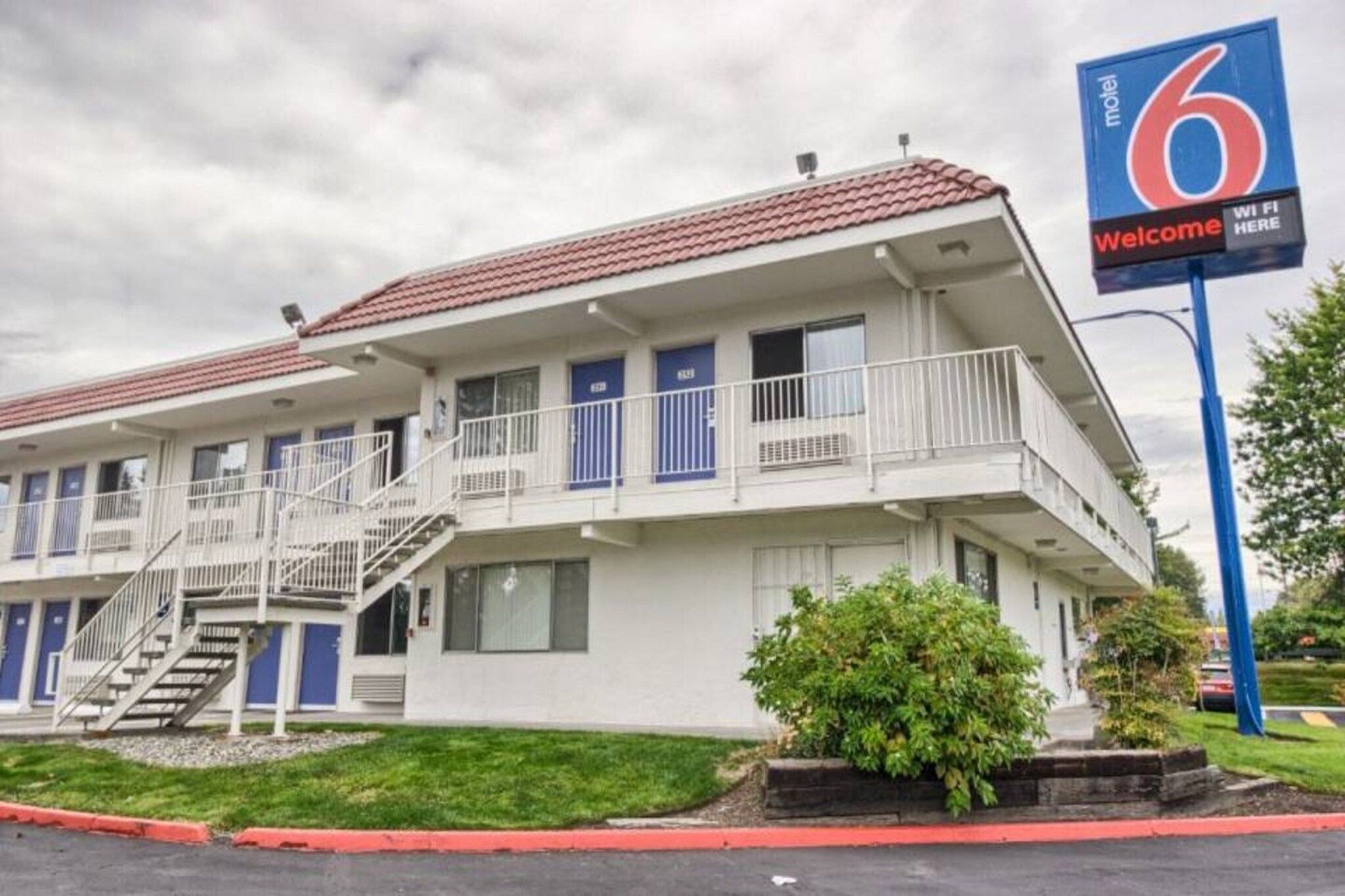 A motel with a red-tiled roof, multiple balconies, and a sign indicating WiFi availability.