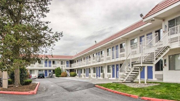 Un motel con cortile centrale, diverse camere dotate di balconi e un’area parcheggio.