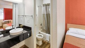 Una camera d'albergo con un letto, un bagno completo di doccia, lavandino e WC.