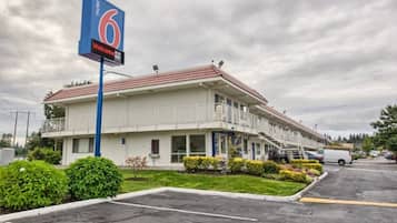 A motel with a large sign, a parking lot, and a building with a red roof.