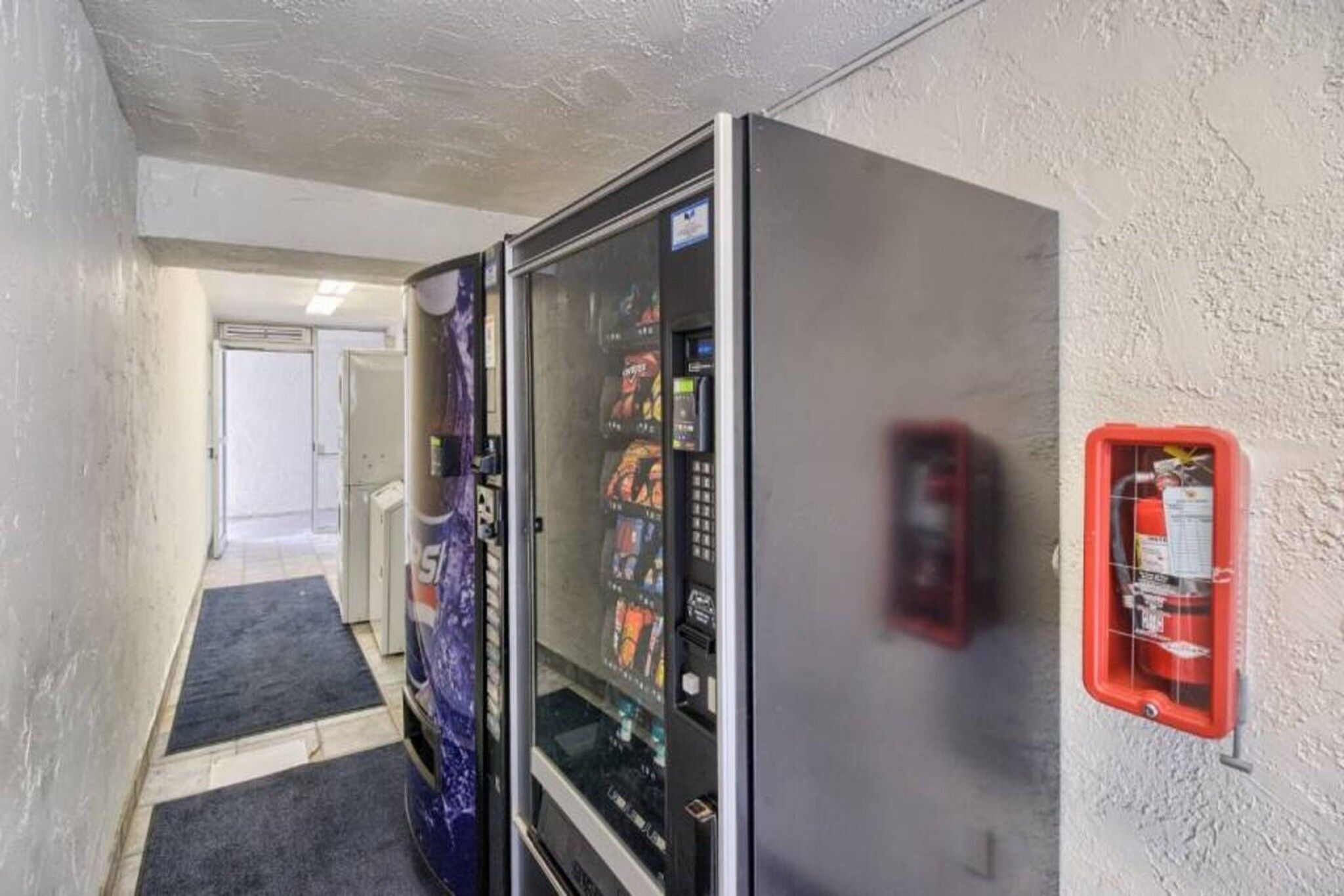 Un corridoio con distributori automatici e un estintore fissato al muro.