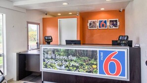 A hotel reception desk with a sign that reads 'We'll leave the light on for you.' - 2 Full Beds | Non-Smoking (Everett)