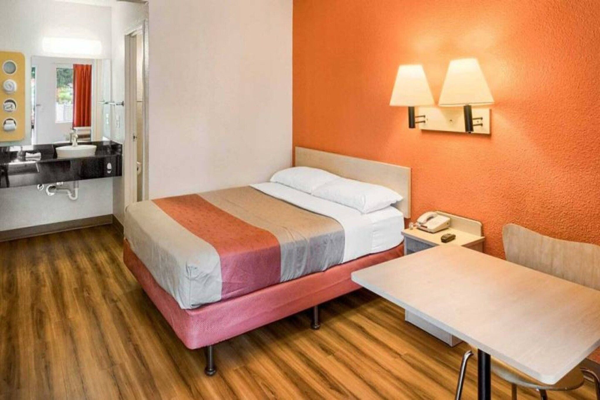 Una habitación de hotel con cama, mesita de noche y una pequeña mesa con una silla.