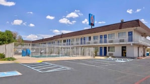 A motel with a fenced parking lot and a clear blue sky. - 1 King Bed Micfridge | Santa Rosa, NM (Santa Rosa NM)
