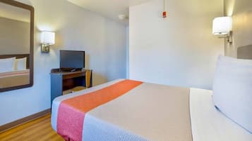 A hotel room with a bed, a television on a stand, and a nightstand.