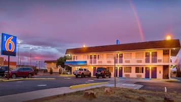 A motel with a large sign, multiple parking spaces, and a building with a flat roof.