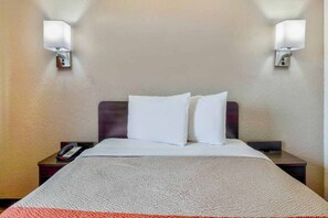 Ein Hotelzimmer mit einem Bett, zwei Nachttischlampen, einem Telefon und Teppichboden.