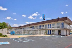 A motel with a fenced parking lot and a clear blue sky. - 2 Queen Beds|Micfridge (Santa Rosa NM)