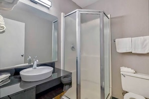 A bathroom with a glass-enclosed shower, a sink with a mirror above it, and a toilet. - 2 Queen Beds|Micfridge (Santa Rosa NM)