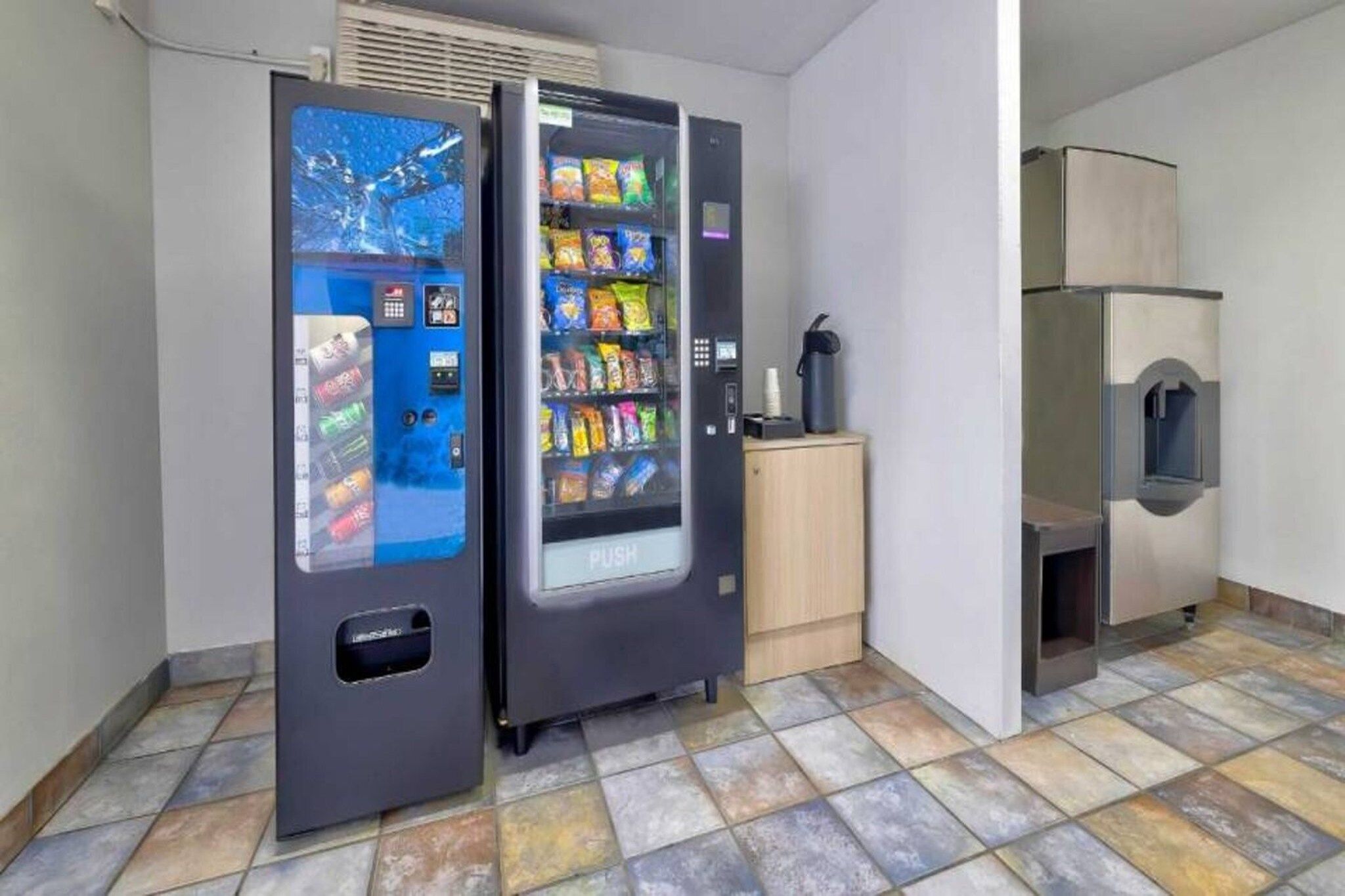 A room with two vending machines, a small cabinet, and a water dispenser.