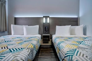 Ein Hotelzimmer mit zwei Betten, einem Nachttisch und einem an der Wand befestigten Telefon.