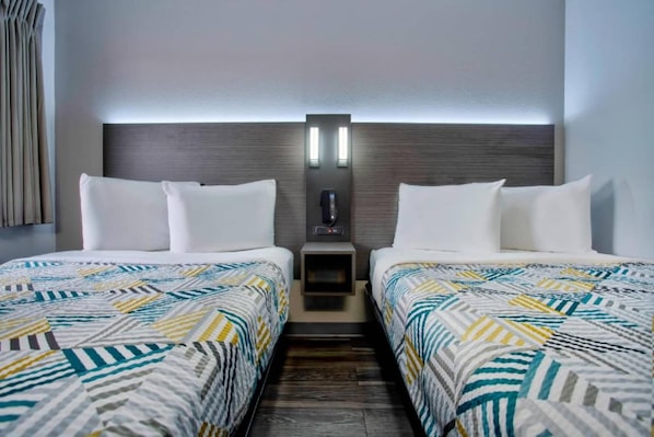 Habitación de hotel con dos camas, una mesita de noche y un teléfono en la pared.