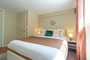 Ein Hotelzimmer mit einem Bett, Nachttischlampen, einer Tür und einem an der Wand befestigten dekorativen Gegenstand.