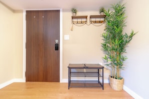 A wooden door, a small table, and a potted plant in a corner. - Warm Modern Stay | 10 mins to Airport & Downtown (Calgary)