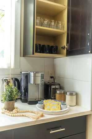Een keuken met een koffiezetapparaat, broodrooster en een kast met glazen.