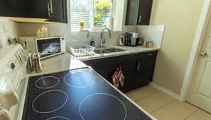 A kitchen with a stove, microwave, sink, and cabinets. - Warm Modern Stay | 10 mins to Airport & Downtown (Calgary)