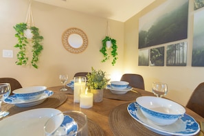 A dining room with a wooden table set for a meal, surrounded by chairs. - Warm Modern Stay | 10 mins to Airport & Downtown (Calgary)