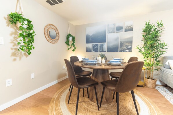 A dining area with a round wooden table, six chairs, and a woven rug. - Warm Modern Stay | 10 mins to Airport & Downtown (Calgary)