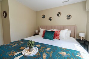 A hotel room with a bed, bedside lamps, a decorative wall, and a tray with a plant and beads. - Warm Modern Stay | 10 mins to Airport & Downtown (Calgary)