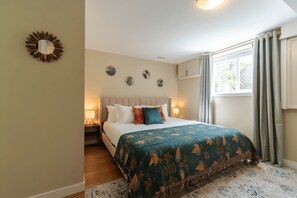 Een slaapkamer met een bed, nachtlampjes, een raam met gordijnen en wanddecoratie.