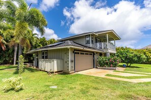 Ein zweistöckiges Haus mit Garage, überdachter Veranda und kleinem Garten mit blühenden Pflanzen.