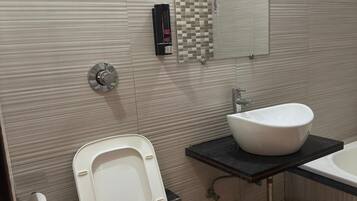 A bathroom with a toilet, bidet, sink, and a shower area.