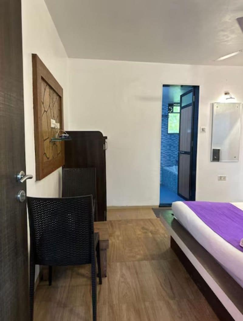 A bedroom with a bed, a chair, a door, and a view of an outdoor area.