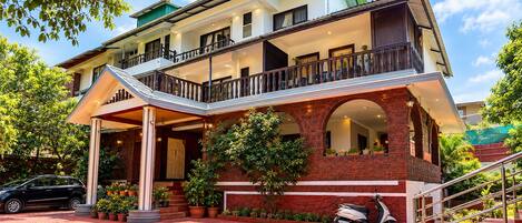 A two-story building with a covered entrance, a balcony, and a staircase leading to the upper floor.