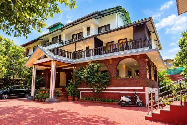 A two-story building with a covered entrance, a balcony, and a staircase leading to the upper floor.