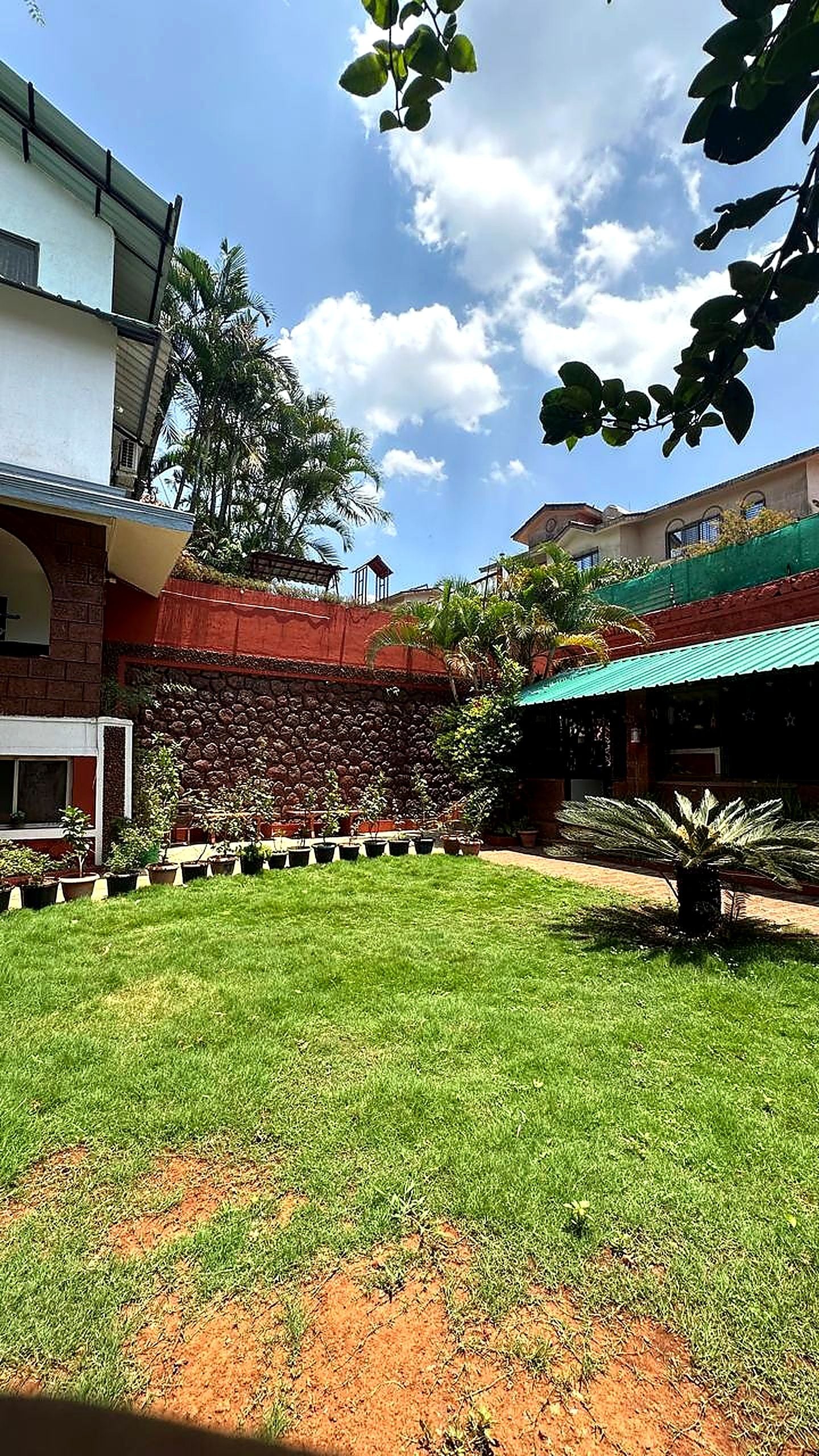 Un patio con césped, un muro de piedra y un edificio con techo rojo.